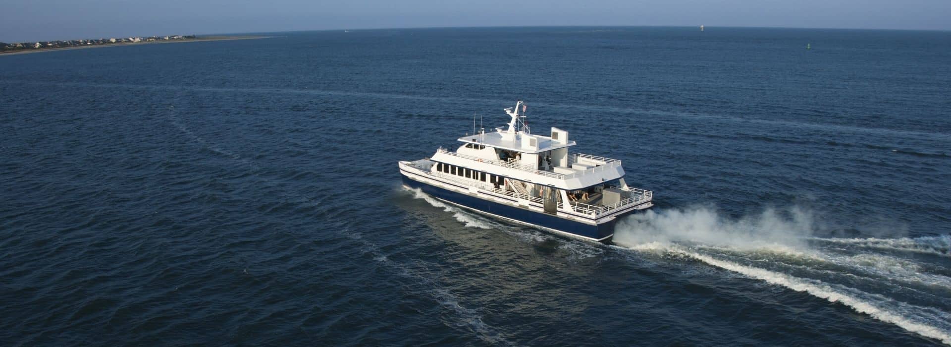 a ferry in the ocean heading toward an island in the distance